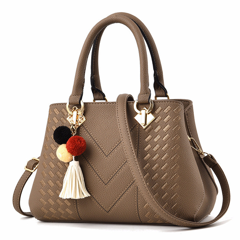 Embossed top handle handbag with pompom
